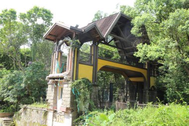 Terk edilmiş eğlence parkının dış kısmında, yemyeşil ağaçlarla çevrili Gotik mimari unsurlara sahip eski bir sarı ve siyah bina yer alıyor. Giriş demirle çerçevelenmiş, çatıda küçük bir heykel duruyor..