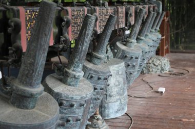 Çin 'in kırsal bölgelerindeki eski ahşap bir binanın kenarına oyulmuş pek çok Çin çanı küçük demirci çekiçleri gibi yan yana duruyor.