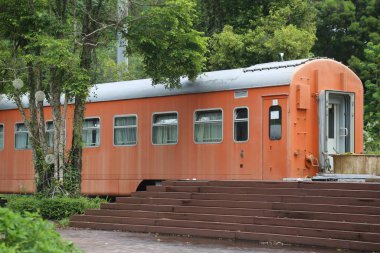 Eski bir turuncu tren vagonu, Çin 'in kırsalında bir tatil yatağı ve kahvaltı olarak kurulmuş. Bir tarafında bir giriş var ve merdivenler oradan zemin kata iniyor, dış duvarın her iki ucunda da iki büyük pencere var..