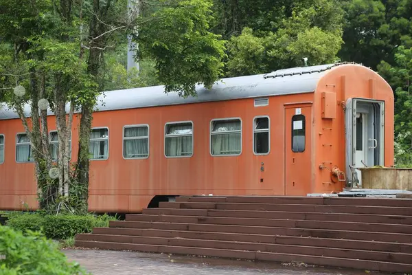 Eski bir turuncu tren vagonu, Çin 'in kırsalında bir tatil yatağı ve kahvaltı olarak kurulmuş. Bir tarafında bir giriş var ve merdivenler oradan zemin kata iniyor, dış duvarın her iki ucunda da iki büyük pencere var..