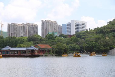 Park şehir merkezinde yer almaktadır, her iki tarafında yüksek binalar ve yeşil ağaçlarla çevrilidir. Önünüzde su seviyesinde yüzen sarı evleri olan birkaç ahşap tekne var..