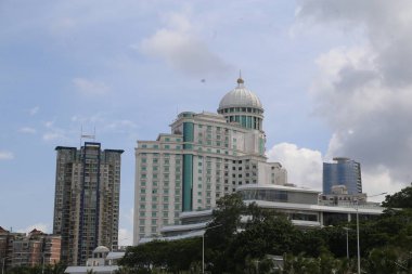 Yeni büyük kumarhane binasının geniş bir görüntüsü beyaz ve yeşil renkli bir şema ve tepesinde başka binalarla çevrili bir kubbe, mavi gökyüzü ve doğal ışıklandırma, iş merkezinin ön tarafındaki açık alandan çekildi.