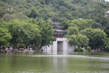 Arkasında bir köprü ve bina olan büyük bir su kütlesi. İnsanlar köprüde oturuyor.