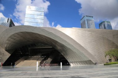 A large building with a large archway. The building is surrounded by trees. There are several people walking around the area
