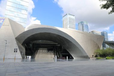 A large building with a large archway. The building is surrounded by trees. There are several people walking around the building