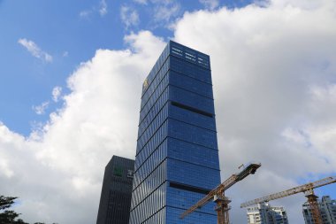 A tall building with a crane in front of it. The crane is orange. The sky is blue