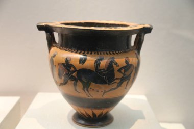 a greek vase painted with an ancient scene of the centaur chiron riding on horseback, in black and brown colors, in the style of ancient greek art, on display at a museum