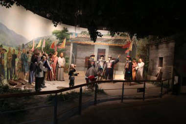 the museum display hall features a large mural depicting the life scenes of rural people in ancient times, with various characters and props displayed on both sides.