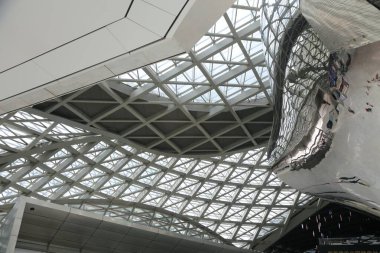 the roof of the airport is made up of steel structural trusses, and there's an abstract sculpture hanging from it that looks like chinese dragon elements. the ceiling features glass curtain walls with white metal frame structures.