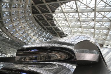A large building with a shiny silver roof. The roof is curved and has a lot of windows