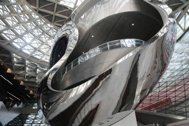 in the steel-framed building, there is an enormous sculpture made of stainless steel and brushstrokes. the exterior walls are decorated with colorful glass panels, creating a futuristic vibe.