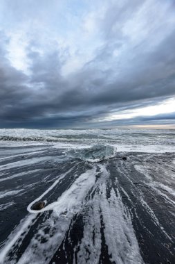  Gizemli İzlanda 'da bulutlu gökyüzü, buz manzaralı elmas plajı.
