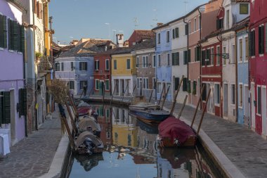 Burano adasının renkli evleri. İtalya 'nın Venedik Bölgesi' nde, Venedik Eyaleti 'nde balıkçı tekneleri ve taş köprüsü olan dar su kanalının fondamenta dolgusu üzerinde çok renkli binalar. Burano kartpostalı