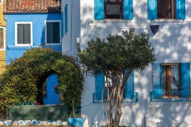 Burano adasının renkli evleri. İtalya 'nın Venedik Bölgesi' nde, Venedik Eyaleti 'nde balıkçı tekneleri ve taş köprüsü olan dar su kanalının fondamenta dolgusu üzerinde çok renkli binalar. Burano kartpostalı