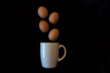 Eggs falling into a white cup on a black background easter clipart