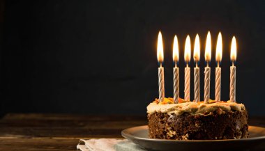 Doğum günü pastası, doğum günü mumları ve arka planda havai fişekler.