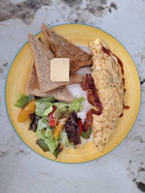 Yumurta, salata, ekmek ve tereyağı kahvaltısı.