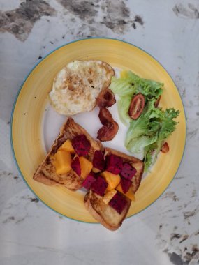 Kahvaltı, salatalı yumurta ve meyveli ekmek.