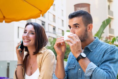 Cep telefonuyla konuşan mutlu bir kadın. Cep telefonu kullanarak gülümseyen bir kız. Kafeteryanın terasındaki çift..