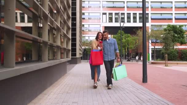 Kaukasisch Paar Lopen Glimlachende Holding Boodschappentassen Browsen Smartphone Apps Winkelen — Stockvideo