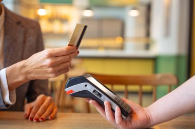 Yakın plan tanınmaz halde. Elinde kredi kartı olan genç bir kadın. Ödeme yapıyor..