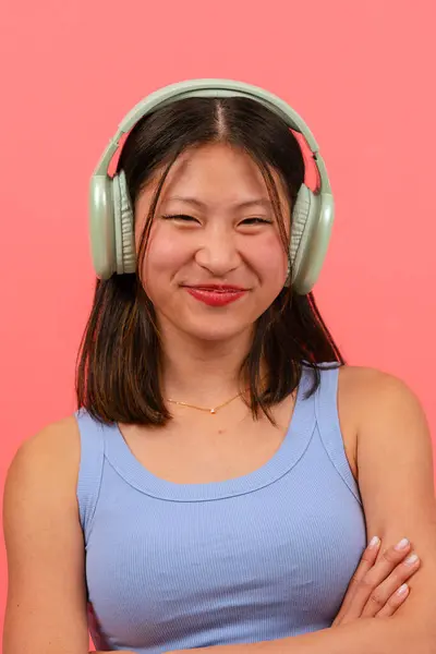 Szczęśliwa Chińska Kobieta Słuchawkami Różowym Tle Ramionami Skrzyżowanymi Patrząc Kamerę — Zdjęcie stockowe