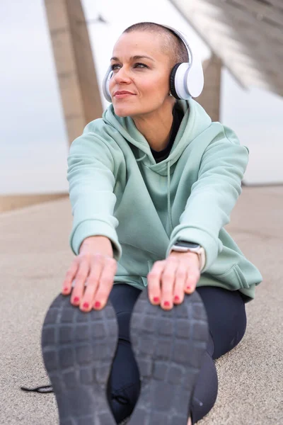 Sporty Woman Sports Headphones Doing Concentrated Stretching Outdoors — Stock Photo, Image