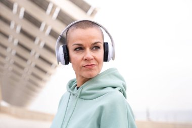 Kulaklıkla gülümseyen sağlıklı kadın. Kadın sabah antrenmanında eğleniyor..
