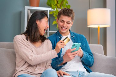 Koltukta oturan çok ırklı genç çift kolay ve güvenli elektronik ödemeler yapmak için tablet numarasına Mutlu Giriş Kredi kartı numarası