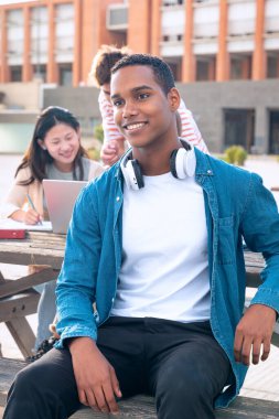 Bir grup üniversite öğrencisi dizüstü bilgisayar kullanıyor. Sınavı dışarıda gözden geçirmek için oturuyorlar.