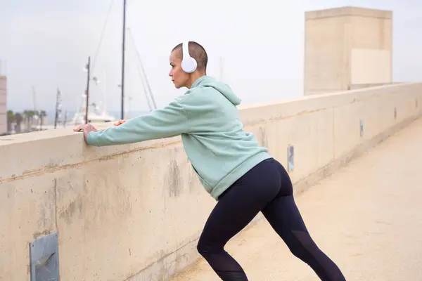 Sporty Woman Sports Headphones Doing Concentrated Stretching Outdoors — Stock Photo, Image