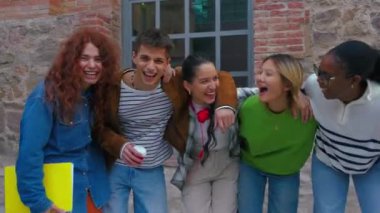 Sınav sonuçlarını kutlamak için ellerinde not defterleriyle gülen bir grup üniversiteli arkadaş. üniversite hayatı konsepti