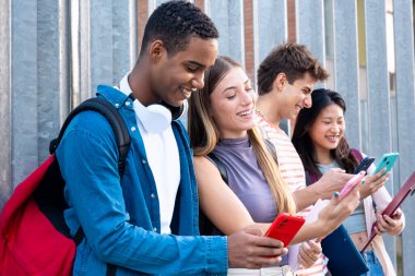  Üç çok ırklı arkadaş cep telefonu aygıtlarıyla sosyal medyayı kullanarak eğleniyor üniversite hayatı kavramı