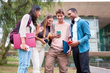 Akıllı telefonlarına bakan bir grup arkadaş kampüste interneti cep telefonuyla tarıyor.