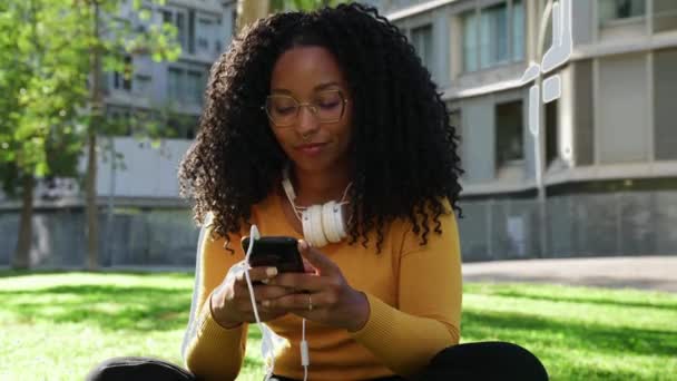 Hermosa Mujer Negra Con Pelo Rizado Gafas Auriculares Usando Teléfono — Vídeo de stock
