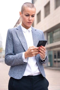 Sonuçlardan memnun olan işkadını ofis binasının dışında sokakta yürüyor, olgun bir patron elinde bir telefon tutuyor, bir uygulama kullanarak mesajlar yazıyor ve internetten haberleri okuyor..