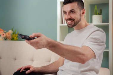 Televizyon, video ve uzaktan kumandalı bir adam. Dairesinde film kanalını değiştiren genç bir adamla.