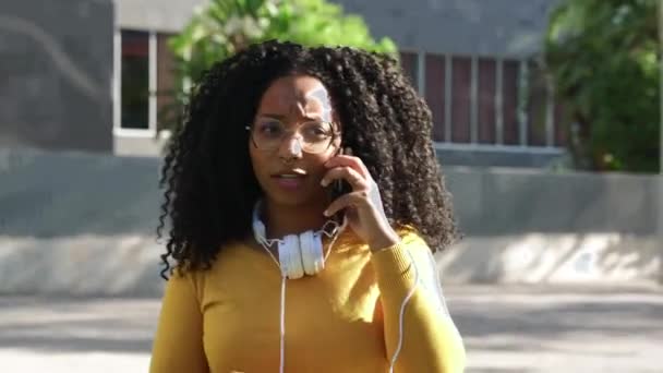 Kıvırcık Saçlı Kulaklıklı Güzel Siyahi Kadın Cep Telefonuyla Ciddi Bir — Stok video