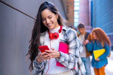 Elinde not defteri olan genç bir öğrenci akıllı telefon uygulamaları ve kablosuz teknolojisi olan sosyal ağlar kullanıyor..