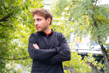 Kollarını kavuşturup kameraya bakan sinirli adam sabah antrenmanında dinleniyor..