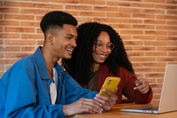 Młoda Uśmiechnięta Wielorasowa Para Siedzi Kanapie Domu Korzystając Telefonu Komórkowego Zdjęcia Stockowe bez tantiem