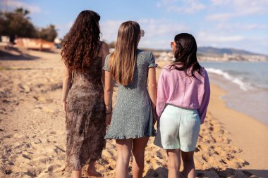 Güneş gözlüklü neşeli çoklu etnik arkadaşlar sahilde mutlu bir şekilde kameraya bakıyorlar..