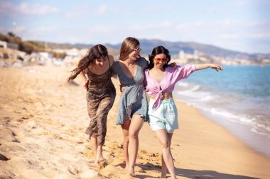 Güneş gözlüklü neşeli çoklu etnik arkadaşlar sahilde mutlu bir şekilde kameraya bakıyorlar..