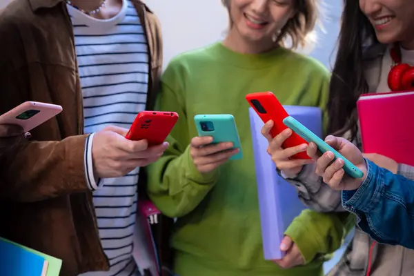 Akıllı telefonlarına bakan bir grup arkadaş kampüste interneti cep telefonuyla tarıyor.