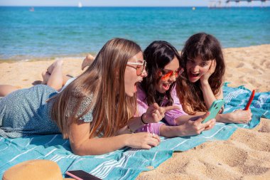 Bir grup gülümseyen, etnik çeşitlilikte kadın tatilde. Güzel ve neşeli Z jenerasyonu kızları cep telefonlarıyla kameraya bakıp poz veriyorlar..