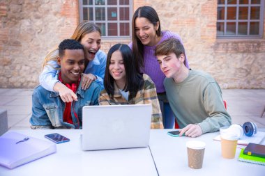 Dizüstü bilgisayarları ve notları olan beş öğrenci sınavları incelemek için kampüsün yanında oturuyor. Dizüstü bilgisayarlarla kampüsün yanında oturuyor ve iletişim kuruyorlar. Yüksek kalite fotoğraf