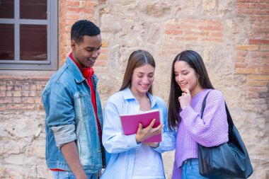 Kampüsteki müfredat notlarını incelerken konuşan ve gülen çok ırklı üniversite öğrencisi arkadaşların kutlu olsun. Çeşitli Amerikan ve Avrupa gençliği