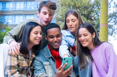 Akıllı telefonlarına bakan bir grup arkadaş kampüste interneti cep telefonuyla tarıyor.