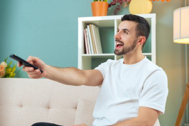 Televizyon, video ve uzaktan kumandalı bir adam. Dairesinde film kanalını değiştiren genç bir adamla.