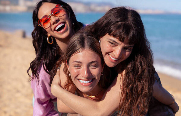 Cheerful multiethnic friends with sunglasses happy on vacation on the beach, looking at the camera.